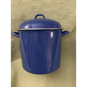 May include: A deep, cylindrical blue enamel stockpot with a matching lid. The pot features two side handles and a small handle on the lid. The exterior has a smooth, glossy finish with a metallic rim around the top edge of the pot base.