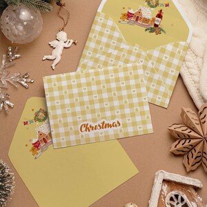 May include: Christmas greeting cards with yellow gingham pattern and matching envelopes. The cards feature the word "Christmas" in a script font. The envelopes have a festive illustration of a gingerbread house and other holiday elements.