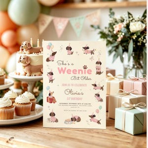 Op de afbeelding: Een crèmekleurige verjaardagsuitnodiging met illustraties van teckels in roze truien en feesthoedjes. De tekst luidt: She's a Weenie Bit Older, JOIN US TO CELEBRATE Olivia's 1ST BIRTHDAY, SATURDAY, OCTOBER 10TH AT 2:00 PM, THE BARKES RESIDENCE, 456 PAWS LANE, AUSTIN, TX, RSVP TO SARAH AT 555-0198.