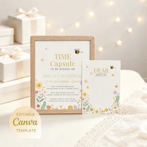 Op de afbeelding: Een houten lijst met een Time Capsule-bord en een bijpassende kaart, beide voorzien van bloemillustraties en een kleine bij. Het bord bevat de tekst Time Capsule to be opened on Amelia's 18th birthday, 17th October, 2042, en extra tekst.