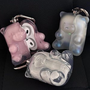 以下が含まれることがあります： 透明、半透明、ピンクのクマ型AirPodsケース4つ。シルバーのキーチェーン付き。2つは虹色、1つはピンク、1つはクリア。ワイヤレスイヤホンを保護し、アクセサリーにするためのケースです。