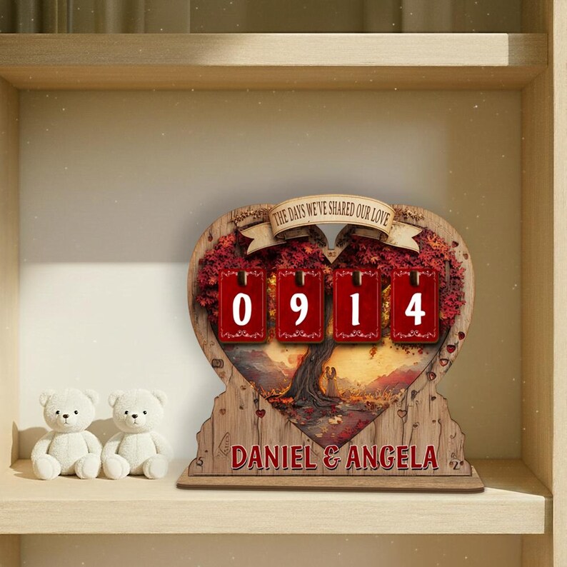 Puede incluir: Un calendario de madera en forma de coraz&oacute;n con el texto "THE DAYS WE'VE SHARED OUR LOVE" y los n&uacute;meros "0914". El calendario tiene un dise&ntilde;o de &aacute;rbol y los nombres "DANIEL & ANGELA". Dos osos de peluche blancos est&aacute;n en primer plano.