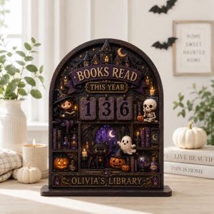 May include: A dark, arched tabletop countdown calendar featuring the text BOOKS READ THIS YEAR and OLIVIA'S LIBRARY. The display includes a witch, a skeleton, a black cat, ghosts, pumpkins, and three rotating number blocks showing 136.