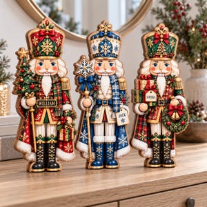May include: Three decorative nutcracker figures featuring intricate holiday designs. The left figure holds a tree and is labelled William. The centre figure holds a snowflake staff and is labelled Jack. The right figure holds gifts and is labelled Sophia.