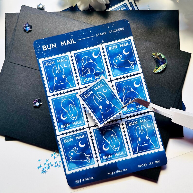 May include: A sheet of nine blue and white bunny stamp stickers with a starry night sky background. The stickers feature a bunny with a crescent moon and the text "BUN MAIL".