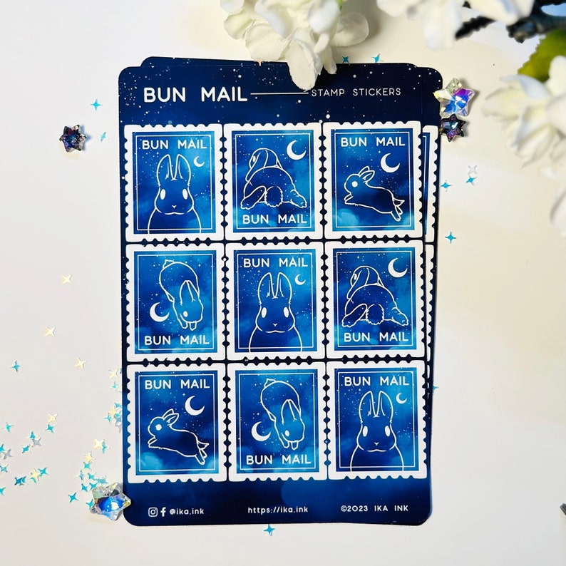 May include: A sheet of nine blue and white bunny stamp stickers with a starry night sky background. The stickers say "Bun Mail" and feature a bunny in different poses.