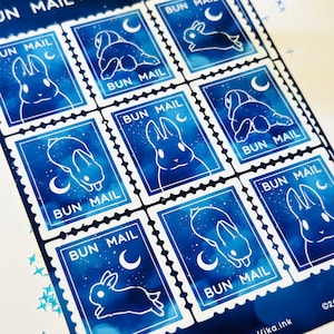 May include: Nine blue and white bunny stamps with the text "BUN MAIL" and a crescent moon. The stamps have a watercolour-like background with white stars.