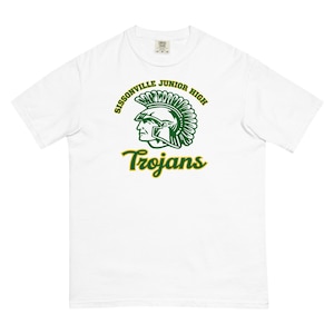 Puede incluir: Camiseta blanca con un gráfico verde y dorado. El gráfico presenta el perfil de una figura con casco con las palabras "Sissonville Junior High" y "Trojans". La camiseta está hecha de un material suave y cómodo.