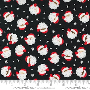 May include: Black fabric with a repeating pattern of white snowflakes and red and white Santa Claus faces. The fabric has a ruler with the words "moda" and "www.modafabrics.com" printed on it.