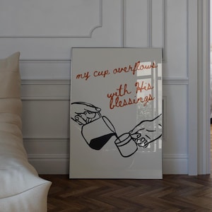 Puede incluir: Un cuadro rectangular con un dibujo lineal minimalista en negro de dos manos vertiendo líquido de una jarra en una taza pequeña. El texto "my cup overflows with His blessings" aparece escrito en una fuente cursiva de color marrón rojizo.