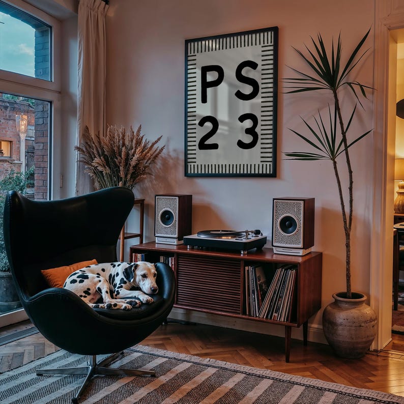 May include: A black egg chair with a Dalmatian dog resting on it. A wooden cabinet with a record player and speakers is in the background. A framed artwork with the text "PS 23" hangs on the wall.