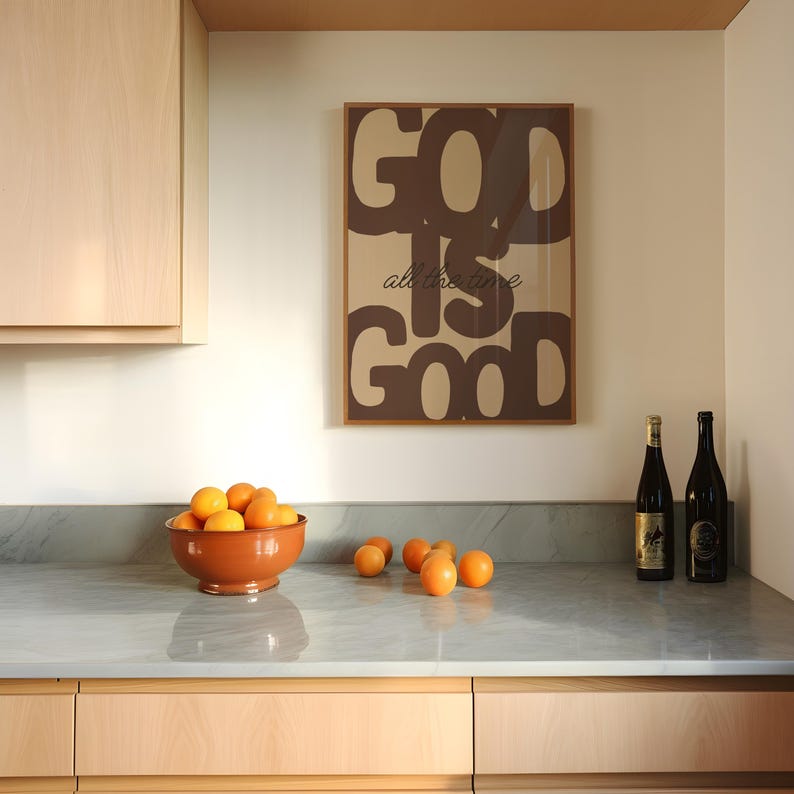 May include: A rectangular wall art print in a brown frame featuring the text GOD IS GOOD in large, bold, dark brown letters with the phrase all the time in a smaller, cursive script font centred between the larger words on a tan background.