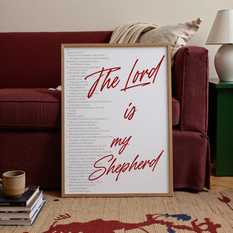 May include: A framed print with the words "The Lord is my Shepherd" in red script. The print is displayed on a patterned rug, leaning against a burgundy sofa. The text of Psalm 23 is printed in black.