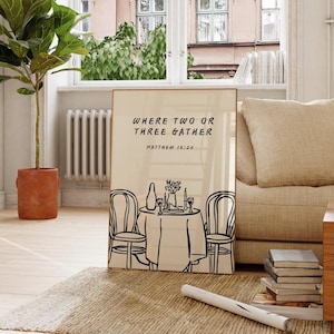 Puede incluir: Una lámina decorativa rectangular con fondo beige y un dibujo de líneas negras que muestra una mesa puesta para dos con sillas, una botella, copas y flores. El texto dice: WHERE TWO OR THREE GATHER MATTHEW 18:20 en una fuente negra sencilla.