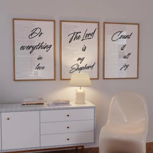 May include: Three rectangular wall art prints in light wood frames featuring white backgrounds with black text. The left print reads Do everything in love, the center reads The Lord is my Shepherd, and the right print reads Count it all joy.