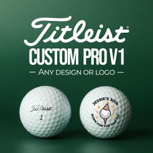 Puede incluir: Dos pelotas de golf Titleist blancas. Una tiene el número 1, la otra un diseño personalizado con el texto "Jessie's 30th" y "Born for the Par-Tee". El fondo es verde oscuro.