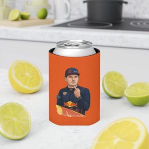 May include: Orange can cooler featuring a portrait of a man in a blue racing suit and a cap. The man is giving the middle finger. The cooler has a silver top and is surrounded by lemon and lime slices.