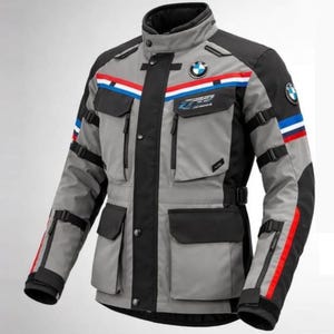 Pode incluir: Casaco de motociclismo cinza e preto com o logótipo da BMW. O casaco apresenta riscas vermelhas, brancas e azuis no peito e nas mangas, vários bolsos e correias ajustáveis. O casaco tem o texto "RACING" no peito.