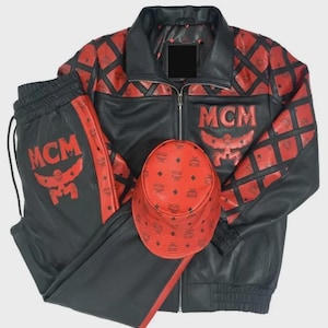 Könnte beinhalten: Schwarzes und rotes Leder-Trainingsanzug-Set mit Jacke, Hose und Bucket Hat. Jacke und Hose haben rote Akzente und das MCM-Logo. Der Bucket Hat ist rot mit einem sich wiederholenden MCM-Logo-Muster.
