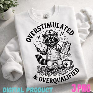 以下が含まれることがあります： 白のスウェットシャツ。看護師の制服を着たアライグマの白黒イラストで、注射器とクリップボードを持っています。「OVERSTIMULATED & OVERQUALIFIED」の文字。医療用品と医療バッグが含まれています。