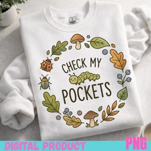Peut inclure: Sweat-shirt blanc avec un motif circulaire représentant une chenille, une coccinelle, des feuilles et des champignons. Le texte "CHECK MY POCKETS" est au centre. Le bas de l'image contient le texte "DIGITAL PRODUCT" et "PNG".