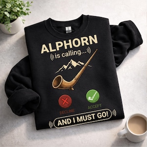 May include: Black sweatshirt with the text "ALPHORN (is calling...)" and an illustration of an alphorn, mountains, and accept/decline buttons. The phrase "AND I MUST GO!" is also printed on the sweatshirt.