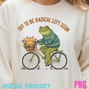 May include: Cream-colored sweatshirt with a whimsical illustration of a frog riding a bicycle with a cat in a basket. The frog wears a striped sweater. Text reads "OFF TO BE RADICAL LEFT SCUM" and "DIGITAL PRODUCT PNG".