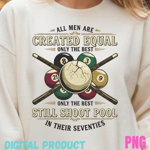 Op de afbeelding: Crèmekleurige sweatshirt met een pool-thema grafisch ontwerp. Het ontwerp bevat poolballen, gekruiste keuen en de tekst "ALL MEN ARE CREATED EQUAL ONLY THE BEST STILL SHOOT POOL IN THEIR SEVENTIES." De woorden "DIGITAL PRODUCT" en "PNG" zijn ook zichtbaar.