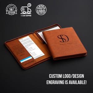 May include: A tan leather portfolio with a custom logo and the name "Samira Daniel" engraved on the cover. The portfolio is open, revealing a notepad and documents. The text "CUSTOM LOGO/DESIGN ENGRAVING IS AVAILABLE!" is at the bottom.