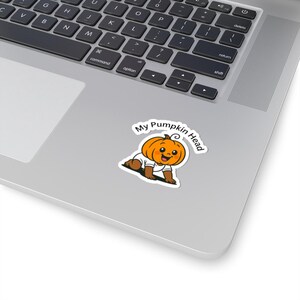 May include: A sticker featuring a cartoon baby with a pumpkin head. The baby is wearing a white onesie and crawling. The text "My Pumpkin Head" is in a circular design above the baby.