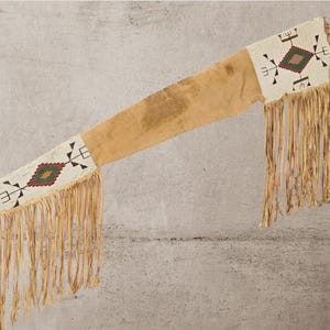 May include: A tan leather sheath with beaded white panels featuring a diamond pattern in red, green, and black. The sheath has long, fringed edges, possibly of Native American origin.