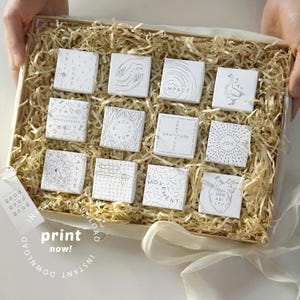 May include: A wooden box filled with straw, holding twelve white square cards with black line drawings and text. The cards feature words like "Connection" and "Impact." A tag reads "good" and "print now!"