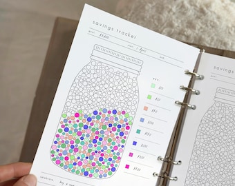 May include: A savings tracker page with a mason jar design. The jar is filled with colorful dots representing savings milestones. The text "savings tracker" and a goal amount are at the top. The text "buy a new sony dslr !!!" is at the bottom.