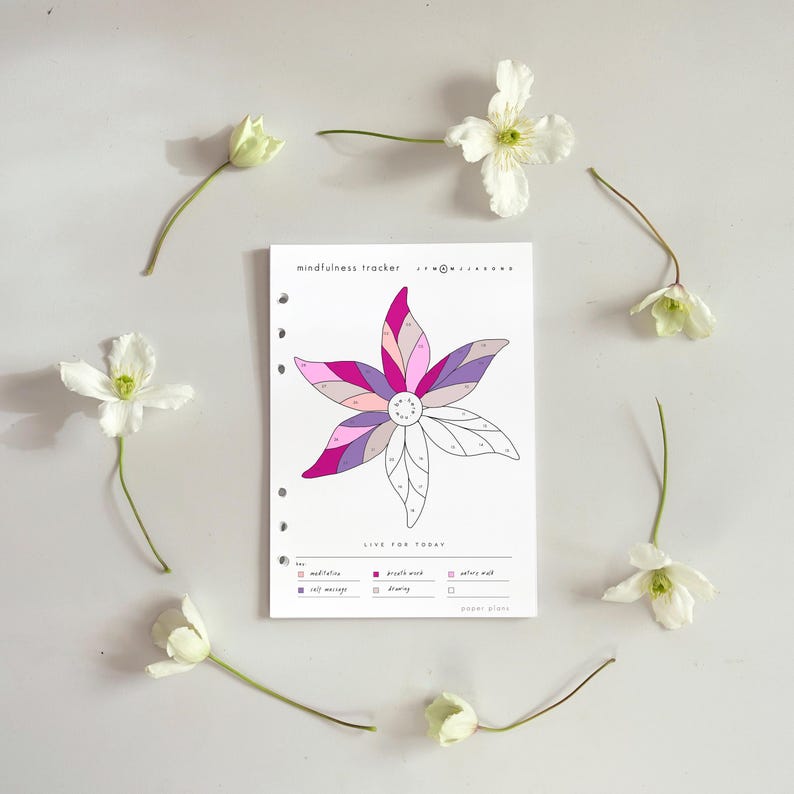 Puede incluir: Una p&aacute;gina de planificador blanca con un dise&ntilde;o floral en tonos rosas, morados y grises, rodeada de flores blancas. El texto "mindfulness tracker" y "LIVE FOR TODAY" son visibles. El planificador tiene perforaciones para una carpeta de anillas.