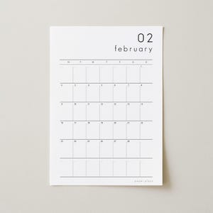 May include: A minimalist white paper calendar for February. The calendar grid is in black, with the days of the week across the top. The month and date, "02 february", are printed at the top. The brand name "paper plans" is at the bottom.