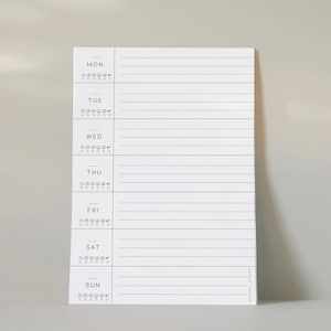 May include: A white weekly planner notepad with a minimalist design. Each day of the week is labelled with a section for notes and a small icon. The notepad has the words "paper plans" printed at the bottom.