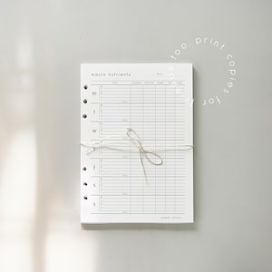 May include: A white paper planner with the words "macro nutrients" at the top. The planner is bound with a string and has columns for meal, calories, protein, carbs, and fat. The days of the week are listed down the side.
