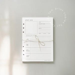 May include: A stack of white plant care sheets tied with twine. Each sheet has a section for plant details, care instructions, and common issues. The text "plant care" and "paper plans" are visible.