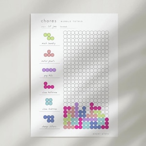 Könnte beinhalten: Ein weißes Aufgaben-Tracker-Blatt mit der Überschrift "chores BUBBLE TETRIS" und einem Raster aus Kreisen. Auf der linken Seite sind Aufgaben wie "wash laundry" und "water plants" mit entsprechenden farbigen Kreisformen aufgelistet. Die rechte Seite zeigt ein großes Raster, in dem einige Kreise mit verschiedenen Farben ausgefüllt sind.