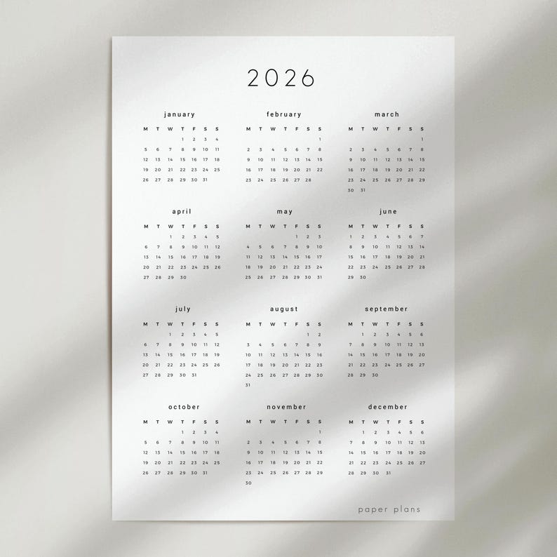 May include: A minimalist 2026 calendar printed on white paper. The calendar features a simple design with the year at the top and months arranged in rows. Each month displays the days of the week and dates. The text "paper plans" is at the bottom.
