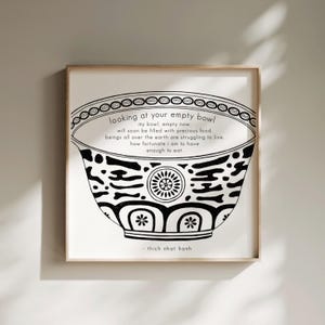 Könnte beinhalten: Gerahmter Druck mit einer schwarz-weißen Illustration einer Schüssel und Text. Der Text lautet "looking at your empty bowl" und ein Zitat von Thich Nhat Hanh. Die Schüssel hat dekorative Muster. Der Rahmen ist hellholzfarben.