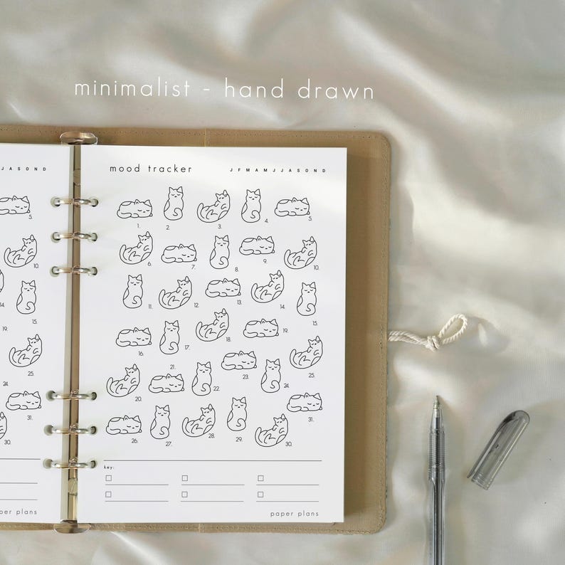 May include: A minimalist planner spread with a mood tracker featuring hand-drawn cat illustrations. The planner is open, revealing a grid of numbered days with cat drawings representing moods. The text "minimalist - hand drawn" is at the top.
