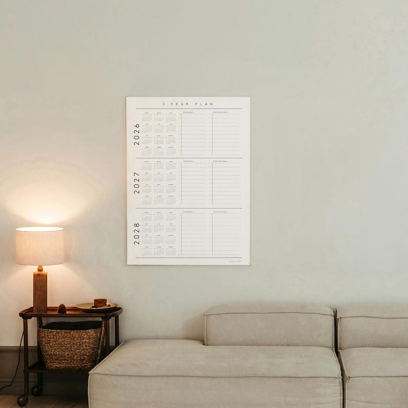 Puede incluir: Un calendario blanco de 2 a&ntilde;os colgado en una pared gris claro. El calendario muestra los a&ntilde;os 2026, 2027 y 2028, con calendarios mensuales y secciones con l&iacute;neas para notas. El texto "2 YEAR PLAN" est&aacute; en la parte superior.