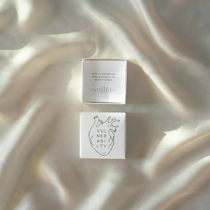 May include: Two small, white square boxes. The top box is open, revealing text that reads "send a voice message today to someone you wouldn't normally" with a sound wave graphic. The bottom box has a heart illustration and the word "VULNERABILITY".