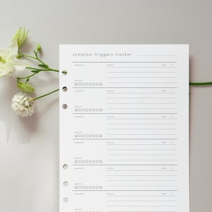 May include: A white symptom triggers tracker sheet with a minimalist design. The sheet includes sections for symptoms, actions, and dates, with a severity scale. The text "symptom triggers tracker" is at the top. A sprig of white flowers is in the upper left corner.