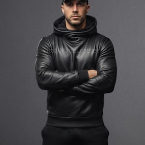 May include: Black leather hoodie with a high collar and long sleeves. The hoodie has a fitted design and is worn with black pants. The image shows the text "Italy Made Leather".