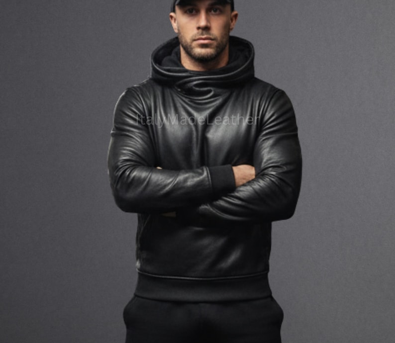 May include: Black leather hoodie with a high collar and long sleeves. The hoodie has a fitted design and is worn with black pants. The image shows the text "Italy Made Leather".