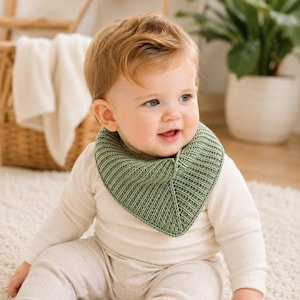 May include: A sage green knitted baby bib with a ribbed texture and a triangular shape. The bib is worn around the neck, featuring a consistent knit pattern throughout the fabric, providing a soft and structured appearance for daily use.