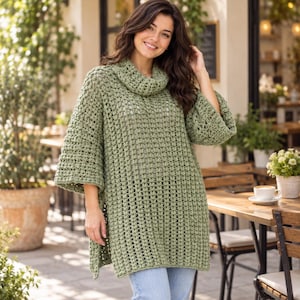 May include: A sage green crochet tunic featuring a loose cowl neckline, wide three-quarter length sleeves, and a textured open-stitch pattern. The garment has a straight hemline with side slits and falls to the mid-thigh, crafted in a soft yarn.