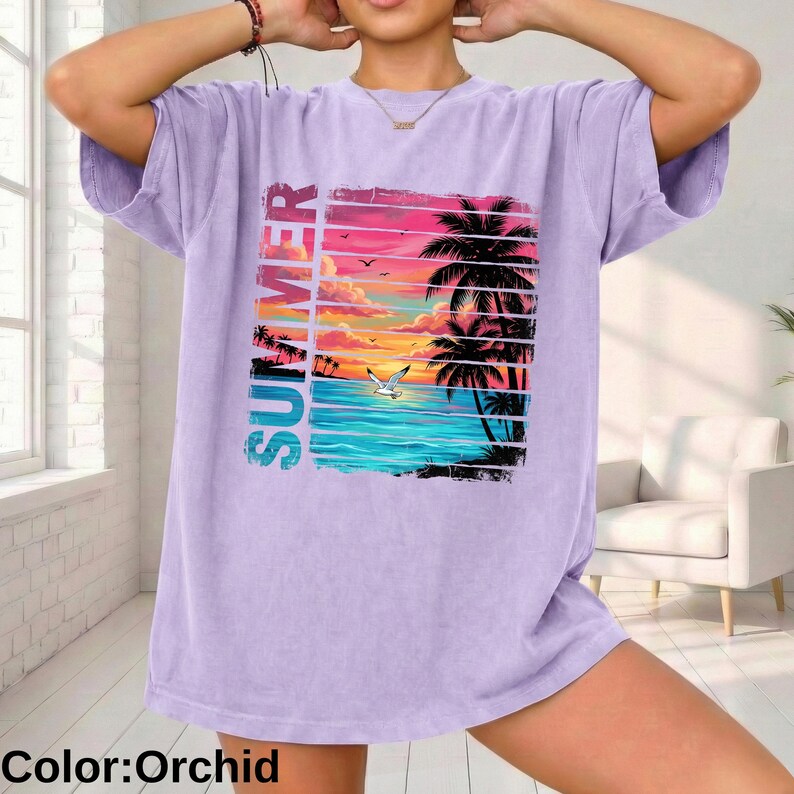 May include: Orchid-colored t-shirt featuring a vibrant summer beach scene. The graphic includes palm trees, a sunset, and the word "SUMMER" in vertical text. The shirt is a relaxed fit.